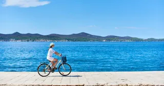 Radfahrerin auf der Uferpromenade von Zadar mit Blick auf die Inseln