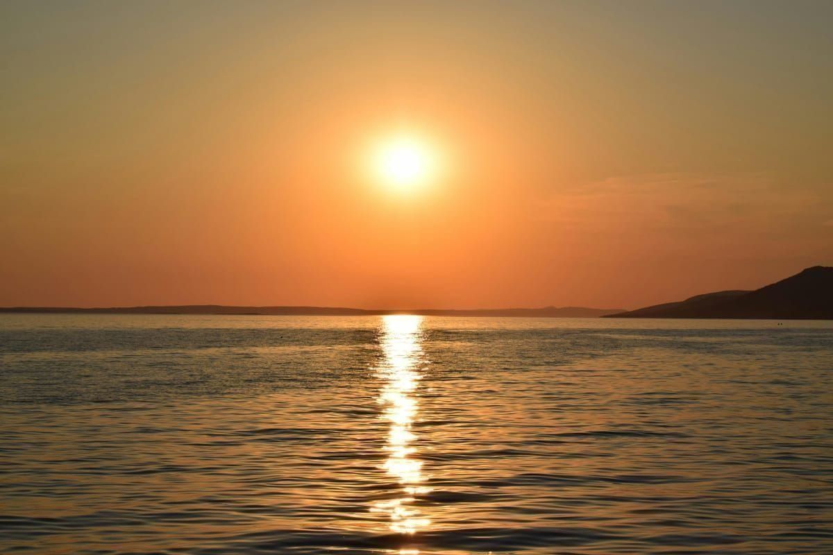 Boot liegt an einer Mooringboje in einer ruhigen Bucht bei Sonnenuntergang