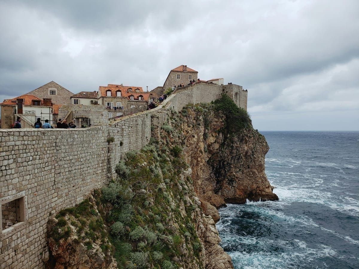 Seekajakgruppe paddelt im türkisen Wasser unterhalb der mächtigen Festungsmauern von Dubrovnik