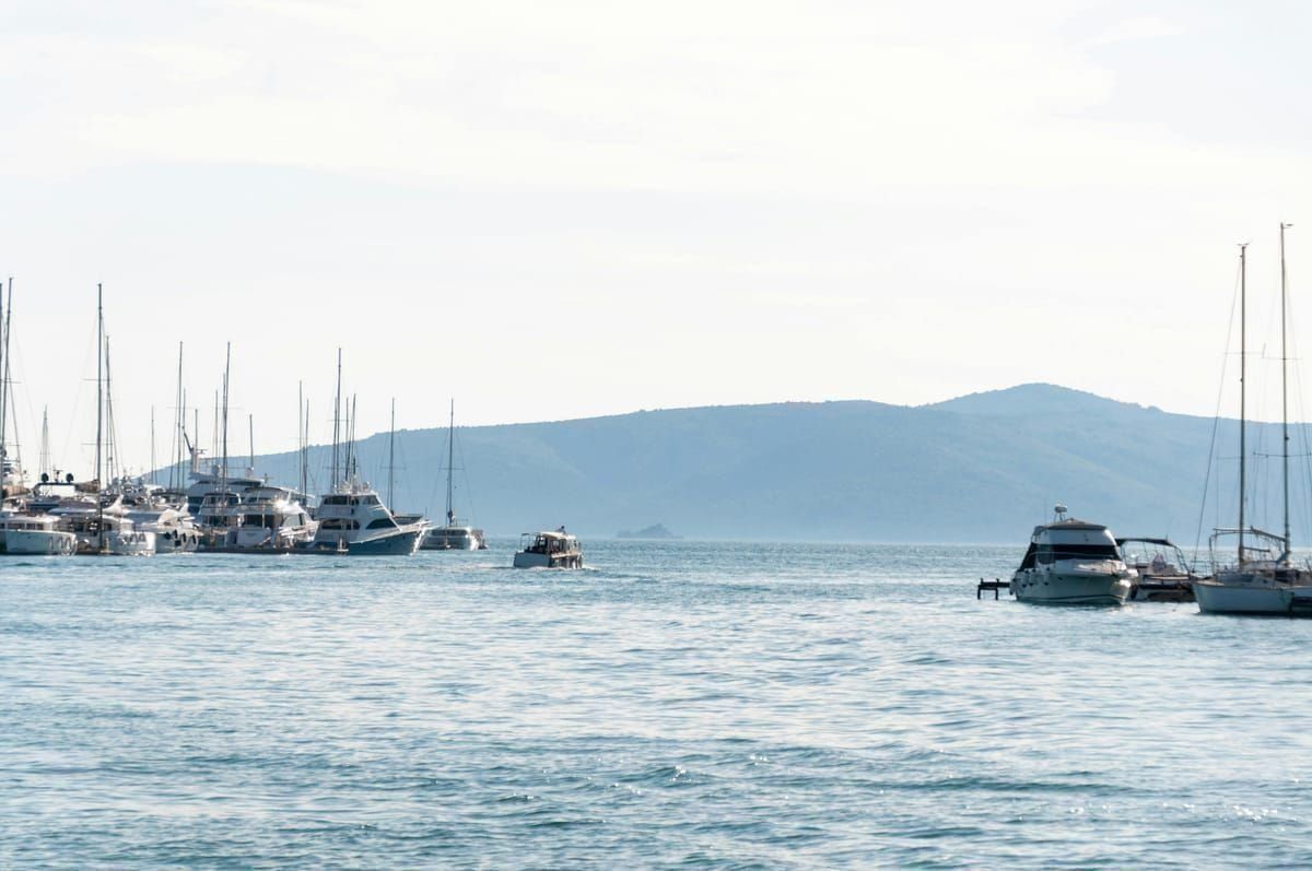 Hafen von Cavtat in der Abenddämmerung mit beleuchteten Häusern und Spiegelung im Wasser