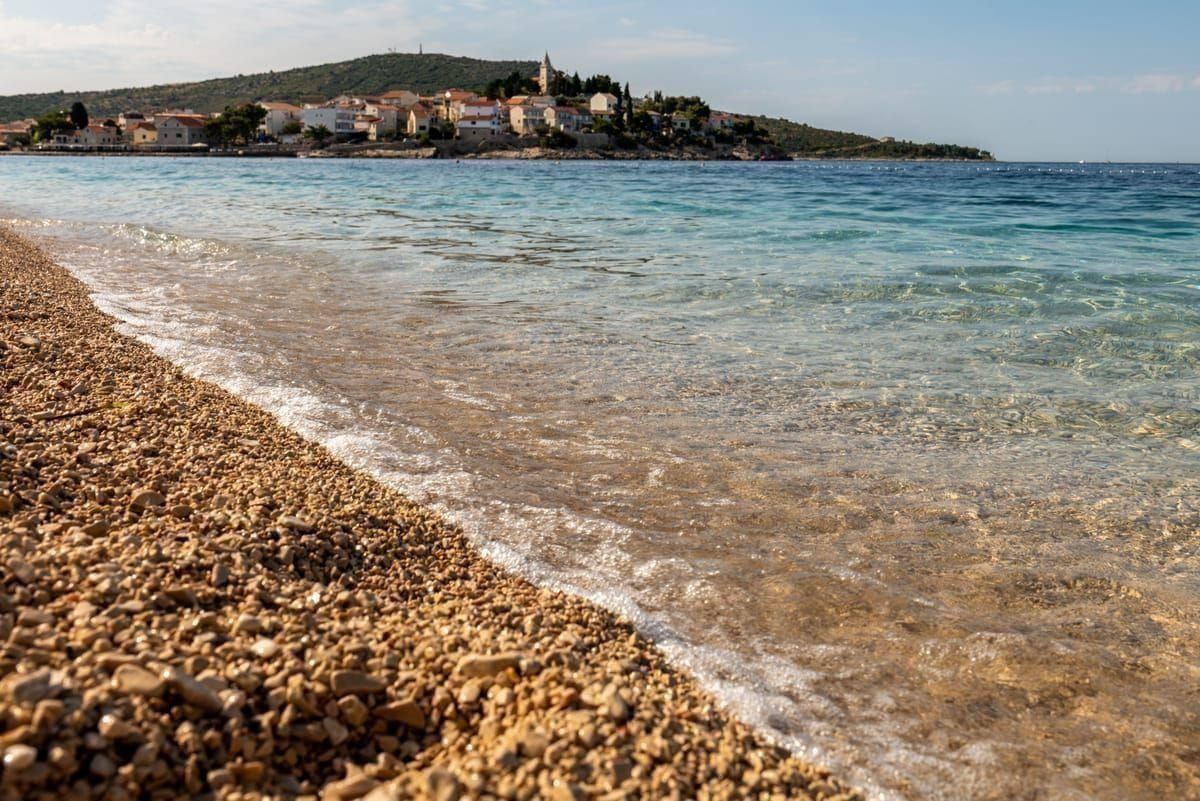 Kiesstrand mit klarem türkisem Wasser und Pinien an der Küste von Cavtat