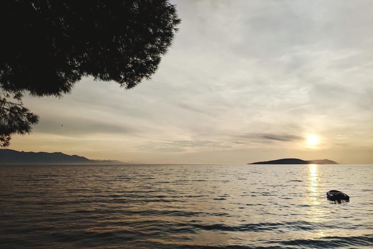 Sonnenuntergang über dem Meer mit Booten in einer ruhigen Bucht auf Silba