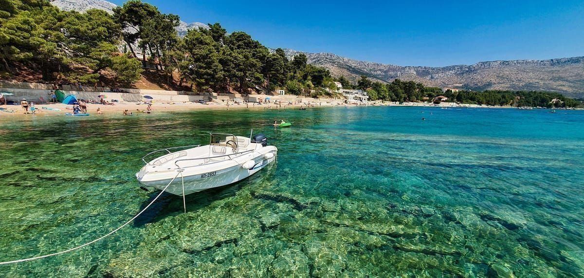 Kieselstrand in Vodice mit Sonnenschirmen und klarem türkisem Wasser