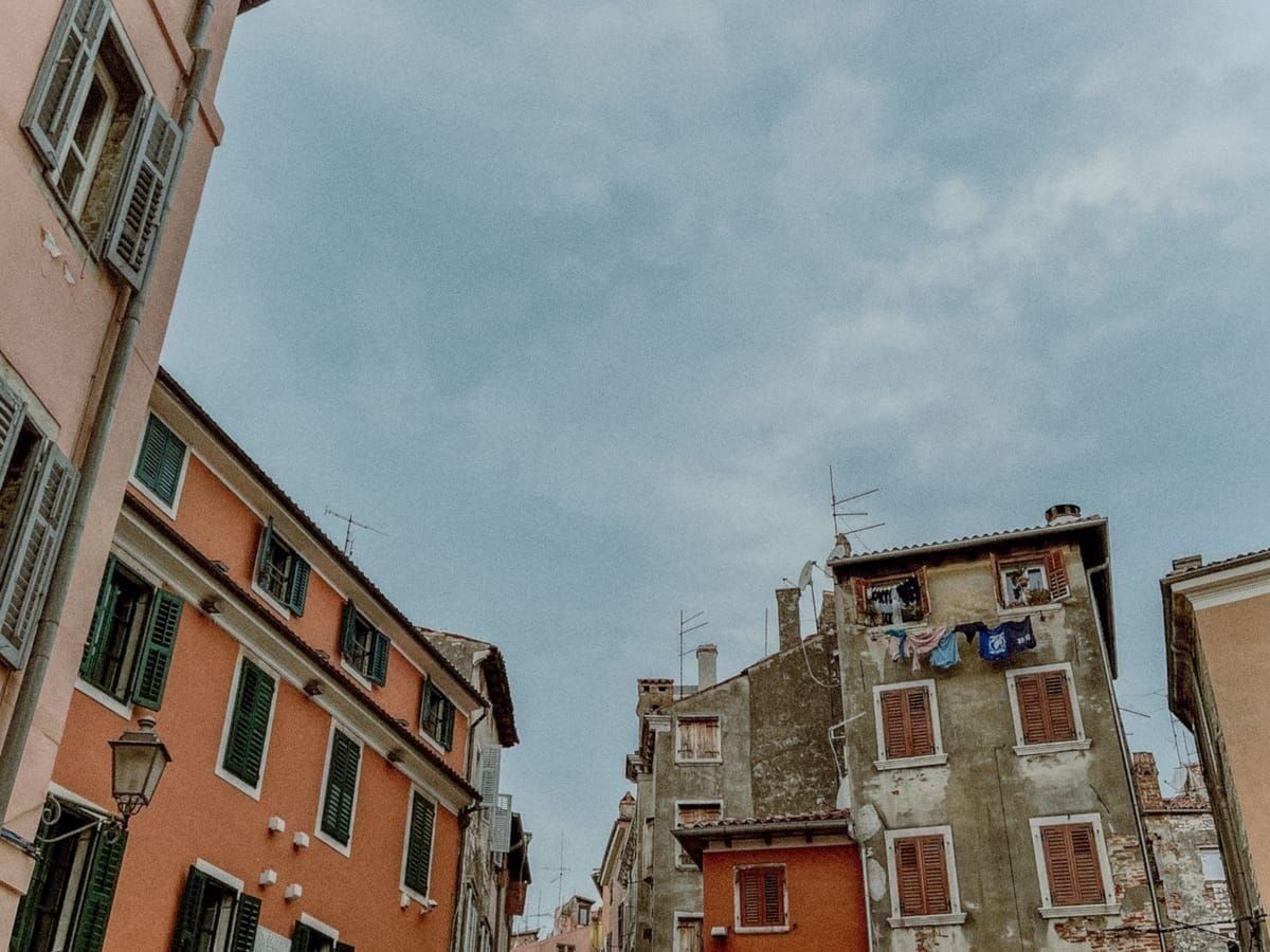 Eine enge, kopfsteingepflasterte Altstadtgasse in Rovinj mit pastellfarbenen Häusern
