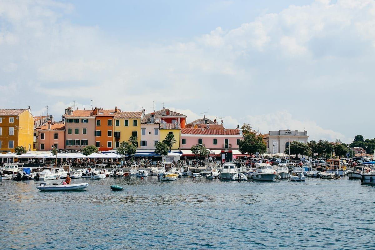 Der Hafen von Rovinj am Abend, pastellfarbene Häuser spiegeln sich im Wasser