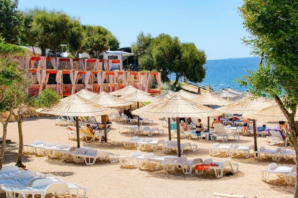 Der Strand Bačvice in Split am Abend, sandiger Stadtstrand mit Strandbars und Lichtern im Hintergrund